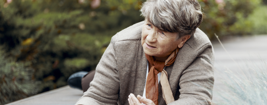 Senior father and his young son sitting on bench by lake in nature, talking.